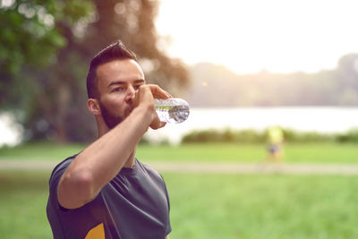 Handsome athlete drinking water in park