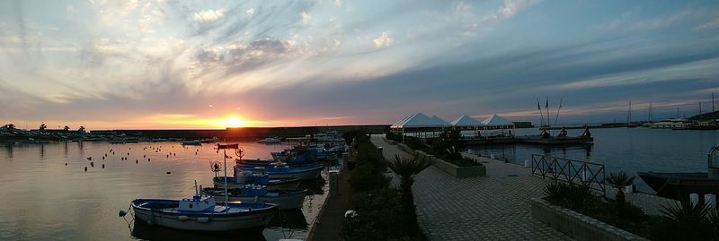 Boats at harbor against cloudy sky