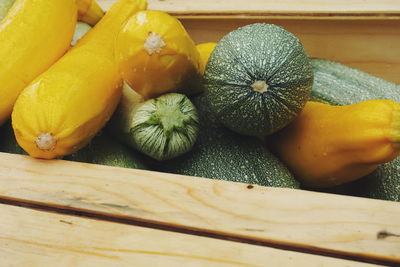 High angle view of wet yellow and green squash in wooden basket for sale at market