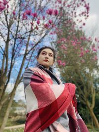 Portrait of beautiful young woman standing against plants