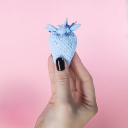 Close-up of hand holding ice cream against pink background