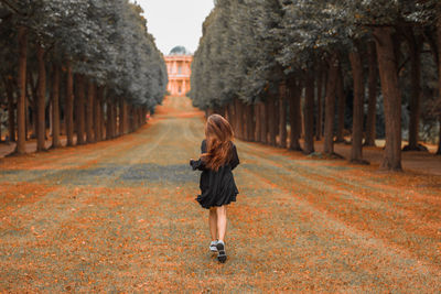 Rear view of woman running amidst trees at park