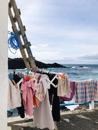 Clothes drying on clothesline by sea against sky