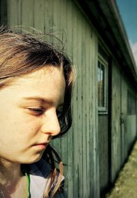 Thoughtful girl looking away by house during sunny day