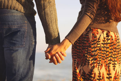 Midsection of couple holding hands