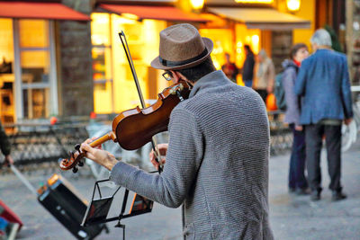 Man playing guitar on street in city