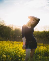 Woman standing on field against yellow flowers