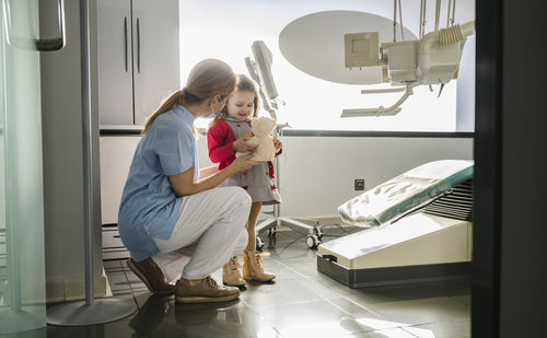 Dentist crouching by cute little girl at dental clinic