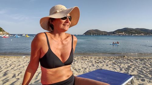 Portrait of woman wearing hat while standing at beach