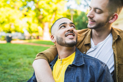Gay couple standing at park while looking away