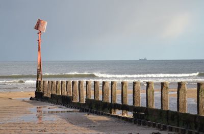 Wooden posts on beach against clear sky