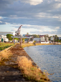 Pier over river by buildings against sky