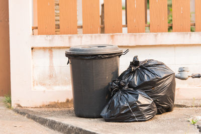 Garbage bin and bags on sidewalk