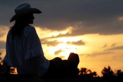 Silhouette man sitting against sky during sunset