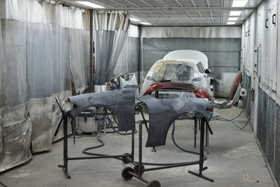 The photograph captures the scene of an automotive workshop, showcasing the process of painting