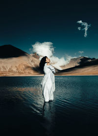 Woman standing in water against sky