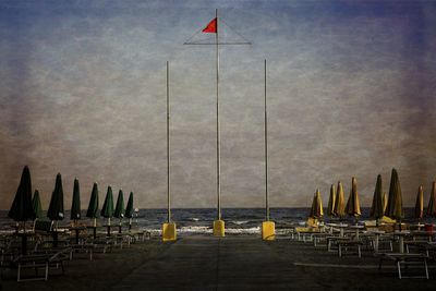 Deck chairs on beach against sky