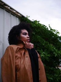 Low angle view of woman wearing jacket against plants