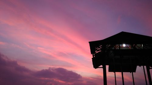 Low angle view of silhouette house against sky during sunset