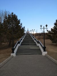 Footpath by street against clear blue sky