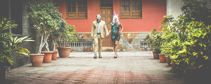 Couple wearing masks while walking on footpath amidst plants