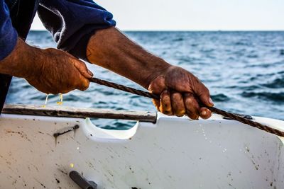 Close-up of hand holding boat against sea