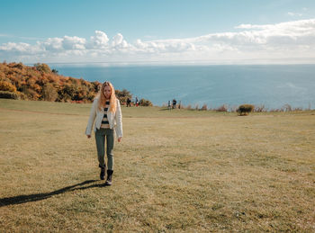 Rear view of woman standing on field against sky