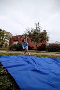 Boy running by blue fabric while practicing handstand in back yard