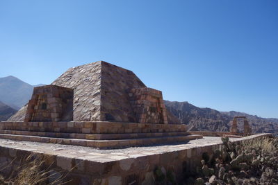 Built structure against blue sky with mountain range in background