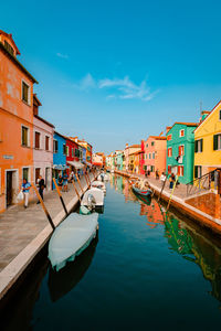 Boats in canal against clear blue sky