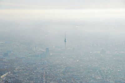 Aerial view of fernsehturm amidst buildings in foggy weather