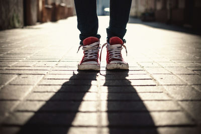 Low section of man standing with shadow on footpath