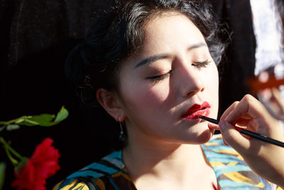 Cropped image of make-up artist applying lipstick to woman