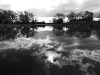 Scenic view of lake by silhouette trees against sky