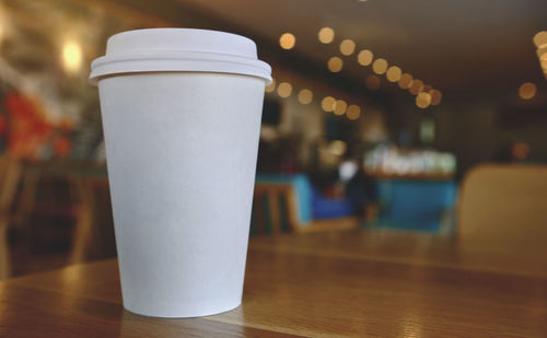 Takeaway cup of coffee in coffee shop background, selective focus. mockup concept.