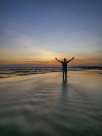 Silhouette man standing on beach against sky during sunset