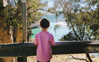 Rear view of girl standing by tree against sky