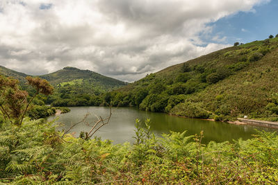 Scenic view of lake by mountains against sky