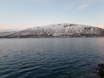 Scenic view of sea and snowcapped mountains against clear sky