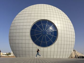 Low angle view of clock hanging against clear sky