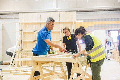 Young female trainees learning from male instructor at workshop