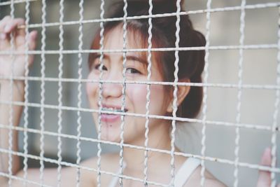 Close-up portrait of a girl looking through fence