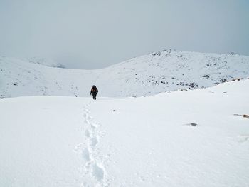 Man skiing on snow covered mountain against sky