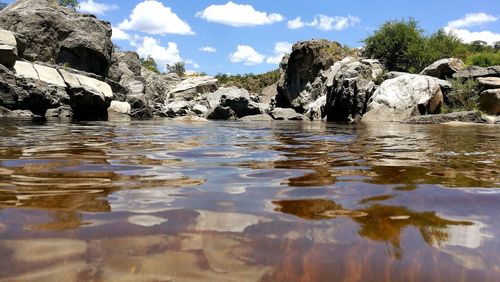 Reflection of rocks in water against sky