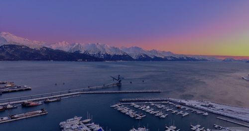High angle view of snowcapped mountains by sea against sky during sunset