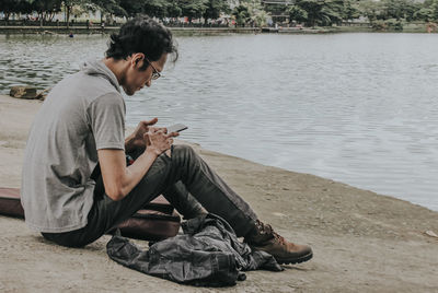 Side view of young man using mobile phone in water