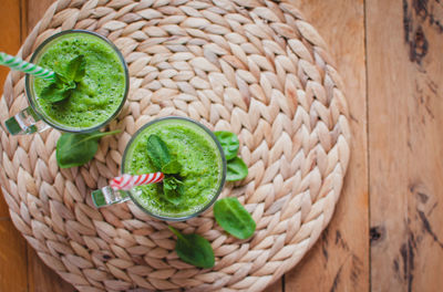 Close-up of green smoothie in a glass with fresh mint and ingredients, top view