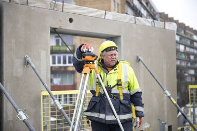  senior surveyor worker working with theodolite or tacheometer transit equipment at construction site 