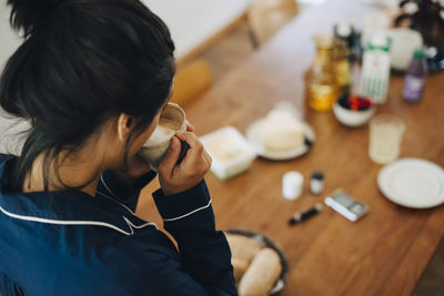 Woman suffering from diabetes drinking coffee by table at home