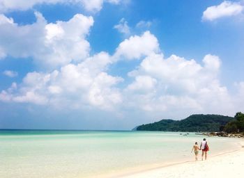 Rear view of man and woman walking at beach